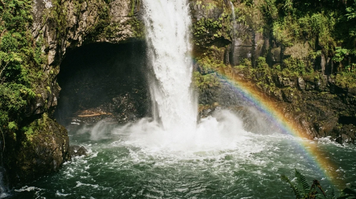 A bright rainbow arcing through the mist at the base of Rainbow Falls in Hilo, Hawaii on a sunny morning